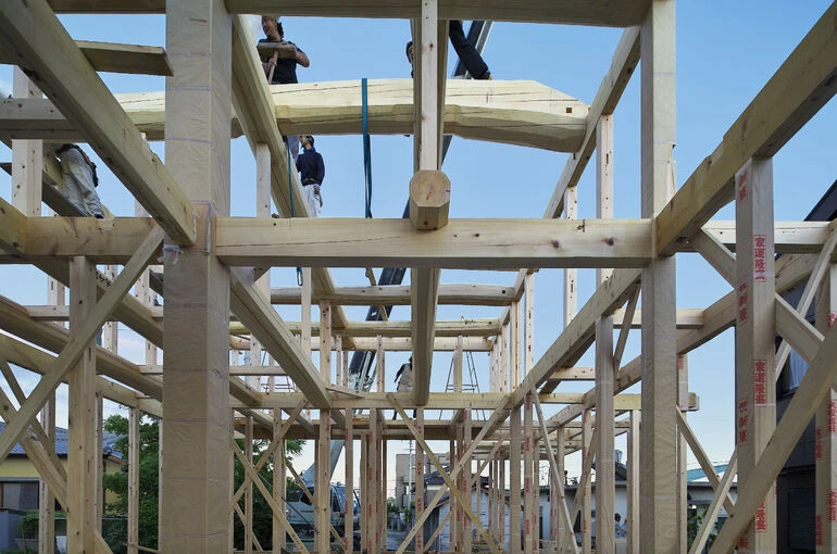 大工職人が手刻みの木組みで構造を組み上げる建前の様子。無垢材で組まれた骨組みが美しく、伝統技術で家の強さを支える施工風景。