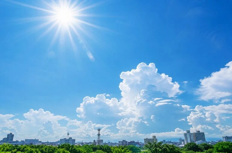 真夏の強い日差しが照りつける青空と入道雲。職人の熱中症対策や夏の現場環境をイメージした風景。